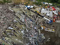 Die Einsatzkr&auml;fte suchen unter anderem mit einem Kran in den Abfall-Massen. - &copy; Jacqueline Hernandez/AP/dpa