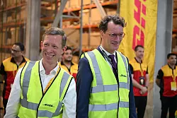 Gut gelaunt gehen DHL-Vorstand Thomas Ogilvie und NRW-Regierungschef Hendrik Wüst durch eine DHL-Lagerhalle in Dubai. - © Wolf von Dewitz/dpa-Zentralbild/dpa