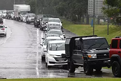 Anwohner standen teilweise stundenlang an, um Sandsäcke zu ergattern. - © Jono Searle/AAP/dpa