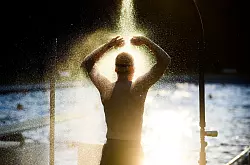 Ist der Körper aufgeheizt, sollte man sich vor dem Baden einmal kurz abbrausen oder etwas Wasser über Arme, Beine und Rumpf spritzen. - © Julian Stratenschulte/dpa/dpa-tmn