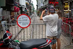 Zwei Touristen aus Brasilien fotografieren die abgesperrte «Train Street» in Hanoi. - © Chris Humphrey/dpa