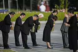 Teilnehmer der Gedenkveranstaltung in Hiroshima halten eine Schweigeminute ab. - &copy; Louise Delmotte/AP/dpa