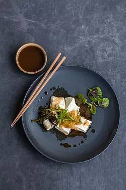 Seidentofu ist weich wie Pudding. Zusammen mit einer Soße aus Sojasoße und Zitrusfrüchten sowie fein geschnittenen Frühlingszwiebeln empfiehlt ihn Kochbuchautorin Claudia Zaltenbach. - © Claudia Zaltenbach/Hädecke Verlag/dpa-tmn