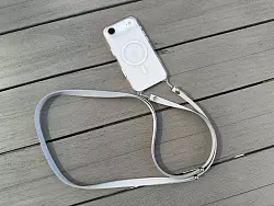 Das neue Crossbody-Band von Apple wird durch kleine Löcher in den iPhone-Hüllen geschlaut und damit befestigt. - © Andrej Sokolow/dpa/dpa-tmn