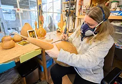 Virginia Lauterbach bearbeitet in ihrer Werkstatt einen Flaschenk&uuml;rbis mit einem Bohrer. - &copy; Julian Stratenschulte/dpa