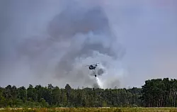 Ein Löschhubschrauber ist beim Waldbrand in der Gohrischheide im Einsatz. - © Robert Michael/dpa