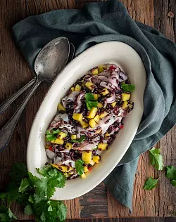 Wenn es mal etwas ganz Exotisches sein soll: Dieser schwarze Reissalat mit Mango und Oktopus sticht auf einer Mitbringfeier sicher heraus. - © Valerie Hammacher/ars vivendi/dpa-tmn