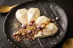 Schokolade, Pistazie, Goldstaub und Schokokugeln in Gold und Violett machen die Panna Cotta zum Highlight. - © Christin Klose/dpa-tmn