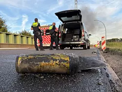 Polizisten stehen hinter einem Metallbehälter. Trümmerteile sollen bei dem Brand Hunderte Meter weit geflogen sein. - © Daniel Bockwoldt/dpa