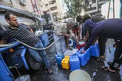 Pal&auml;stinenser f&uuml;llen Beh&auml;lter mit Trinkwasser aus einem Wasserverteilungsfahrzeug auf. - &copy; Mohammed Talatene/dpa