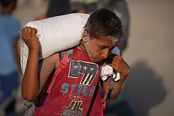 Ein pal&auml;stinensischer Junge tr&auml;gt einen Sack Mehl. (Archivbild) - &copy; Jehad Alshrafi/AP/dpa