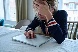 Eine Frau sitzt vor einem geschlossenen Laptop und seufzt. - &copy; Annette Riedl/dpa