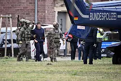 Eine Person wird von Polizeibeamten zu einem Hubschrauber gebracht. - &copy; Uli Deck/dpa