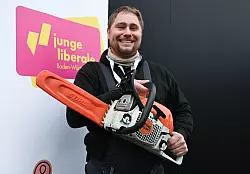 Mit der Kettensäge will Mark Hohensee, Landesvorsitzender der Jungen Liberalen, packt für den Bürokratieabbau symbolisch die Kettensäge aus. - © Bernd Weißbrod/dpa