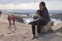 Ein M&auml;dchen und ihre Katze in einem Notlager im syrischen Salqin. - &copy; Anas Alkharboutli/dpa