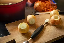 Mit einem Parisienne-Löffel oder einem Kugelausstecher wird die ungeschälte Zwiebel ausgehöhlt. - © Christin Klose/dpa-tmn