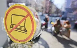 Im Café ILOstan in Berlin weist ein Schild auf das Verbot von Laptops hin. - © Sebastian Gollnow/dpa