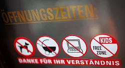 An einer Scheibe der Café-Bar 8tto Grammi weist ein Schild auf das Verbot von Laptops hin - wie auch auf das Verbot für Hunde, Kinderwägen und auf eine kinderfreie Zone. - © Daniel Karmann/dpa