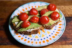 Eine Scheibe Kürbiskernbrot mit Avocado und Tomaten. Viele jüngere Leute in Deutschland sehen sich eher als Avocadobrot- denn Wurstbrot-Typ. (Symbolbild) - © Robert Michael/dpa