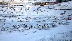Ein Mann geht im Hafen über das zugefrorene Wasser. - © Steffen Trumpf/dpa