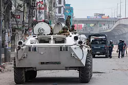 Bangladeschische Militärkräfte patrouillieren auf gepanzerten Fahrzeugen in den Straßen von Dhaka - © Rajib Dhar/AP/dpa