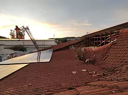 Vom Korb einer Drehleiter heraus kontrolliert ein Feuerwehrmann den eingestürzten Dachbereich. - © Freiwillige Feuerwehr Lauchringen/dpa