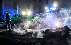 Polizisten stehen hinter einer rauchenden Barrikade im Stadtteil Connewitz in Leipzig. - © Hendrik Schmidt/dpa