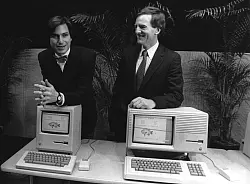 Apple-Mitbegr&uuml;nder Steve Jobs (l) und der damalige Pr&auml;sident von Apple John Sculley stellen am 24. Januar 1984 vor einer Aktion&auml;rsversammlung im kalifornischen Cupertino ihre ersten Macintosh-Computer vor. - &copy; UPI/dpa