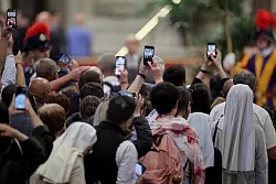 Mit den Smartphones machen Gläubige ein Foto vom toten Papst. - © Christoph Reichwein/dpa