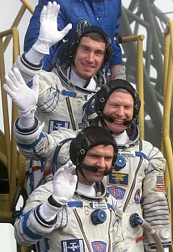 Der Kommandant der ersten Langzeitmission zur Internationalen Raumstation, der amerikanische Astronaut Bill Shepherd (M), und die russischen Kosmonauten Juri Gidsenko (unten) und Sergej Krikaljow (oben) winken, bevor sie auf dem Kosmodrom in das Raumschiff "Sojus-TM-31" einsteigen. (Archivbild) - &copy; Sergei Chirikov/epa/dpa