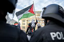 Ein Teilnehmer einer verbotenen Pro-Pal&auml;stina-Demonstration in Frankfurt am Main schwenkt eine Pal&auml;stina-Flagge, w&auml;hrend Polizisten die Situation beobachten. - &copy; Hannes P. Albert/dpa