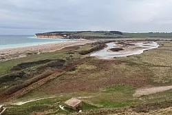 Der Blick von Haven Brow auf Cuckmere Haven: Bei Ebbe kann man den Strand queren, bei Flut ist das zu gefährlich. Der Umweg zur Brücke landeinwärts lohnt sich aber. - © Nathalie Helene Rippich/dpa-tmn