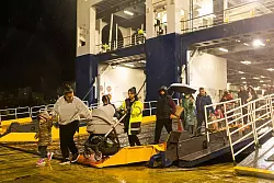 Menschen steigen im Hafen von Piräus von einer Fähre, mit der sie Santorini verlassen haben. - © Socrates Baltagiannis/dpa