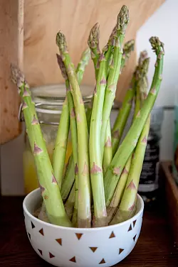 Grüner Spargel bleibt stehend in einem Gefäß mit etwas Wasser frisch. - © Zacharie Scheurer/dpa-tmn