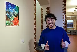 Der junge Mann darf sogar noch ein weiteres Gemälde aufhängen. - © Alex Talash/dpa