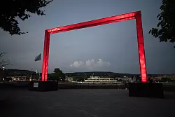 Ein großes rotes Tor, das Teil des Lichtkunstprojekts «Red Goals» zur EM ist, steht am Ufer des Zürichsees - © Sebastian Christoph Gollnow/dpa