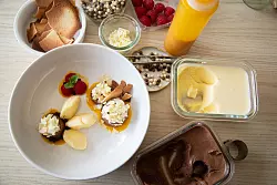 Mangoeis und Schokoladenmousse werden auf Mango- und Erdbeerpüree-Klecksen angerichtet. Splitter von weißer Schokolade und frischen Himbeeren toppen die Kreation. - © Christin Klose/dpa-tmn
