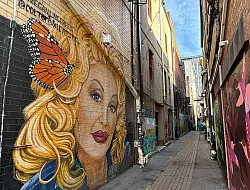 Ein Mural von Dolly Parton in einer Seitengasse von Knoxville: Natürlich hat die berühmte Countrysängerin auch hier gespielt. - © Verena Wolff/dpa-tmn