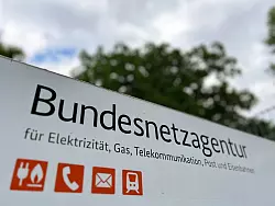 Ein Schild mit der Aufschrift «Bundesnetzagentur» steht vor dem Eingang des Dienstsitzes der Regulierungsbehörde. - © Wolf von Dewitz/dpa
