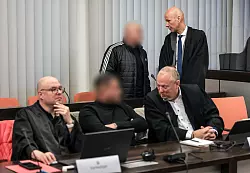 Der Hauptangeklagte (hinten, links) spricht im Gerichtssaal mit seinem Verteidiger Oliver Doelfs (hinten, rechts). - © Oliver Berg/dpa