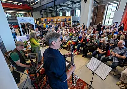 Besucher lauschen in der Hartmannfabrik einem Konzert der „Werkskapelle Naunhof“. Die historische Fabrikhalle wurde für die Kulturhauptstadt umfassend saniert und war als Besucherzentrum für viele Gäste erster Anlaufpunkt. (Archivbild) - © Hendrik Schmidt/dpa