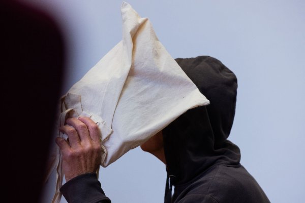 Der Angeklagte sitzt im Landgericht und verdeckt sein Gesicht. - © Rolf Vennenbernd/dpa