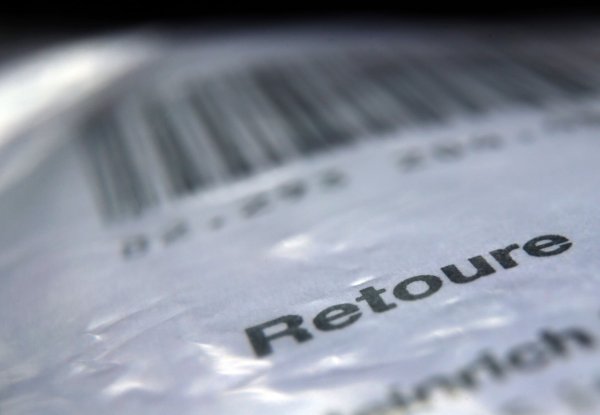 Das Wort «Retoure» steht auf dem Retourenaufkleber eines in Folie verpackten Päckchens. - © Karl-Josef Hildenbrand/dpa