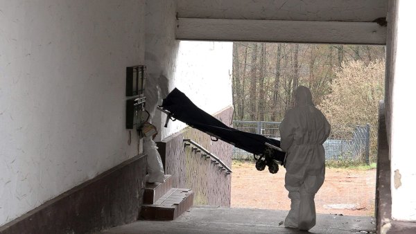 Beamte der Spurensicherung bringen eine Trage in ein Wohnhaus. - © Thorsten Kremers/dpa