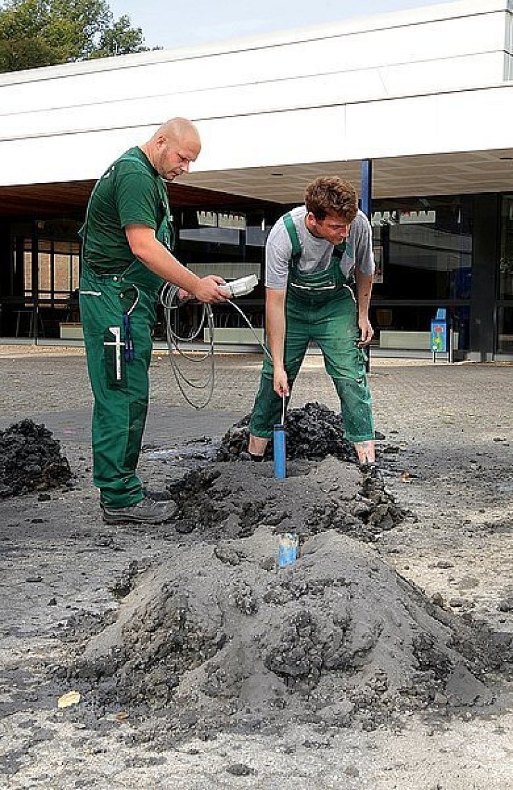 Michael Siegler (l.) und Nico Bradatsch lassen die Tiefensonde in einem Plastikrohr hinunter, das in einem der Bohrlöcher steckt. Das Messgerät zeigt ihnen Metall in der Nähe an. - © FOTOS: WOLFGANG RUDOLF
