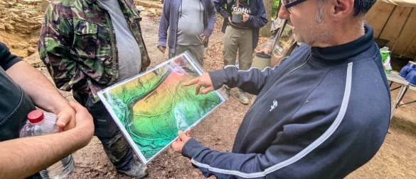 Archäologe Mark Lodwick zeigt mithilfe einer LiDAR-Karte, wo auf dem Gelände vermutlich einst Mauern verliefen. Auf Basis dieser Karte, die mithilfe von Laserimpulsen erstellt wurde, ermitteln die Forscher Stellen für Testgrabungen. - © Yvonne Glandien