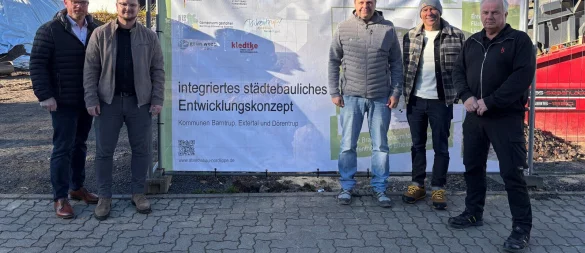 Bürgermeister Friso Veldink (von links), der zuständige Sachbearbeiter Adrian Lücke, Oliver Brundiers (Geschäftsführer Grünwert OWL), Fachbereichsleiter Dirk Süllwold und Rolf Kledtke (Geschäftsführer Kledtke Elektro- und beleuchtungstechnik) stehen vor dem Bauzaunbanner mit der Umsetzungsplanung. Es fehlt Thekla Merfort vom Innovationszentrum Dörentrup. - © Gemeinde Dörentrup