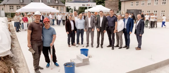 CWS-Bauleiter Daniel Krein und sein "inoffizieller Bauleiter" (vorne links) legten in Anwesenheit vieler "Offizieller" den symbolischen Grundstein für das inklusive Wohnprojekt. - © CWS OWL