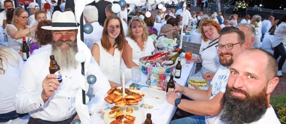 Weiß gekleidet, Snacks auf dem Tisch, ein Getränk in der Hand: Das "Dinner in White" auf dem Lagenser Marktplatz ist ein geselliges Event. - © Nicole Ellerbrake