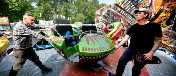 Marktmeister Manuel Schneider (links) packt in Gütersloh beim Aufbau vom "Steamer", einer Art Breakdance, der auch in die Höhe schnellen kann, mit an. Betreiber Geron Langhoff geht ihm zur Hand. - © Andreas Frücht